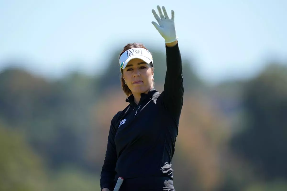 Georgia Hall raises her hand at the fourth tee