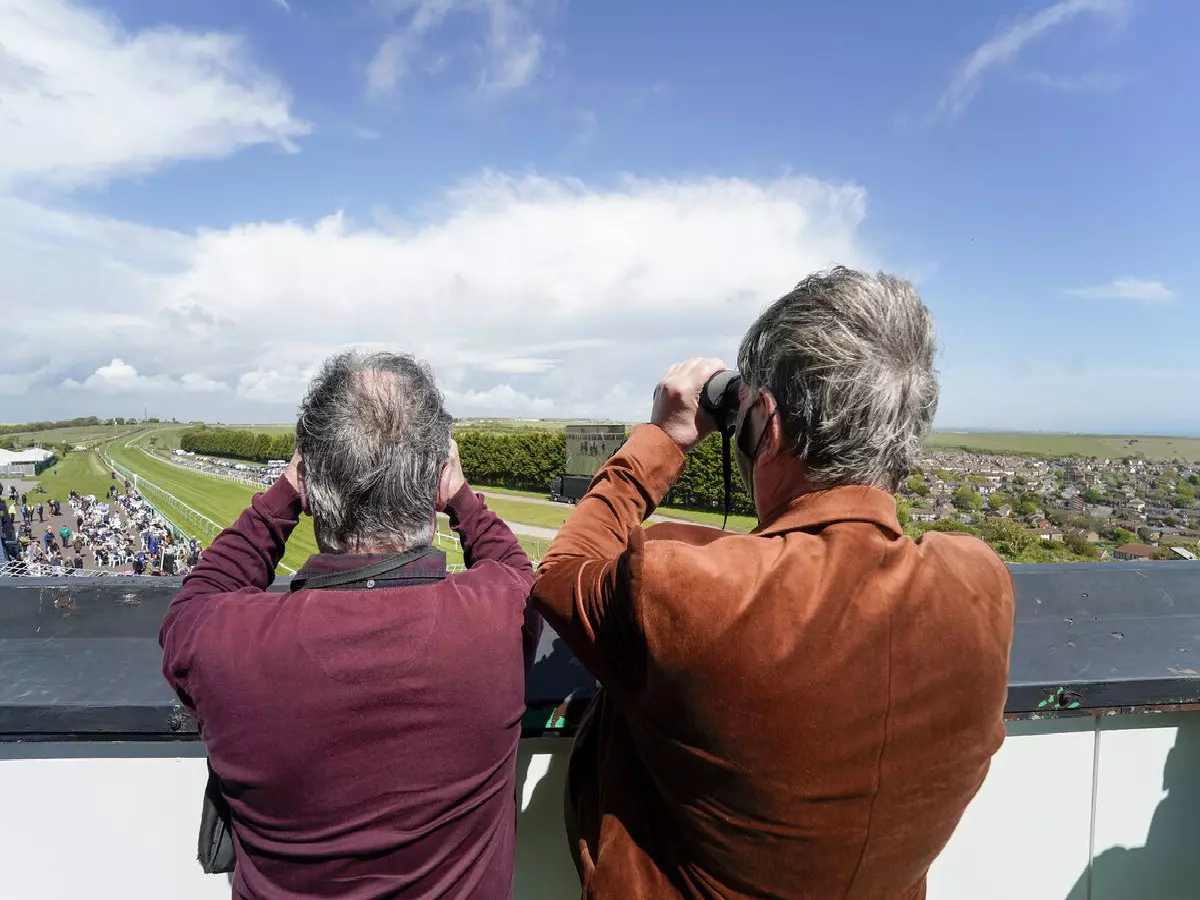 A general view as two racegoers watch the action through binoculars at Brighton Racecourse.