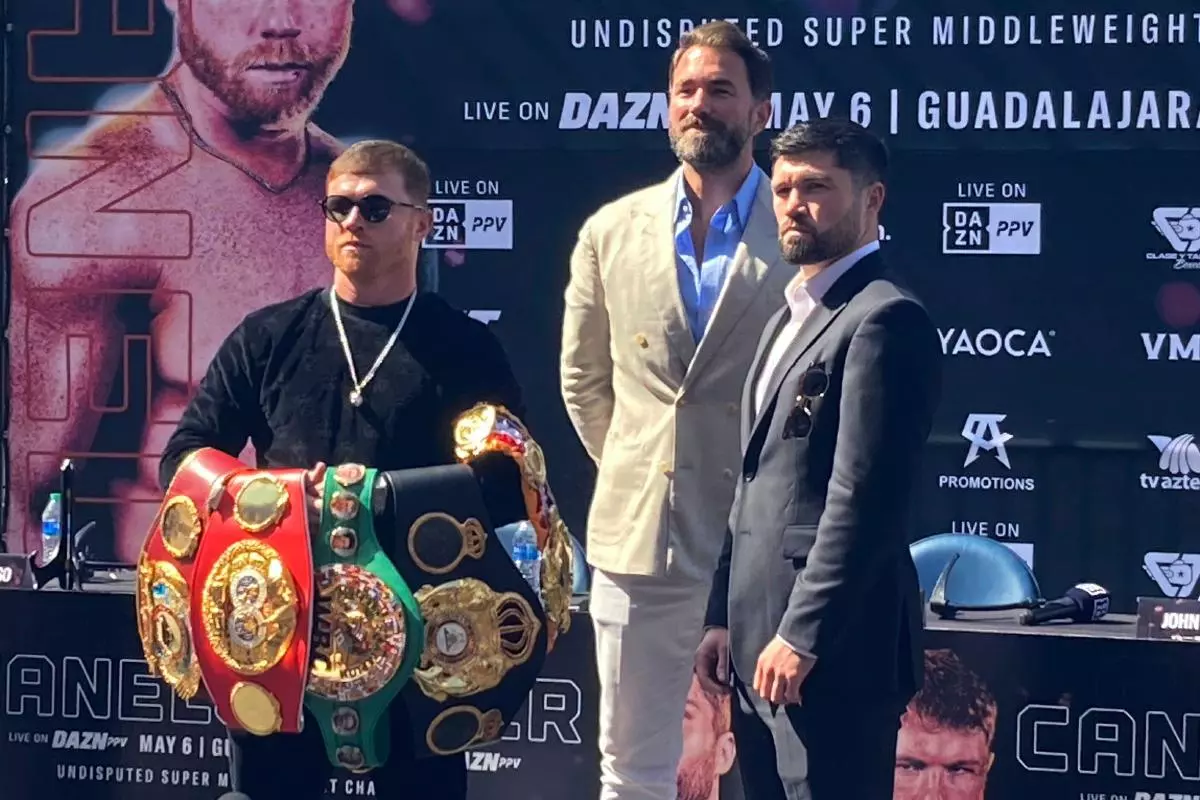 Canelo Alvarez holds up his collection of super middleweight championship belts after facing off with challenger John Ryder