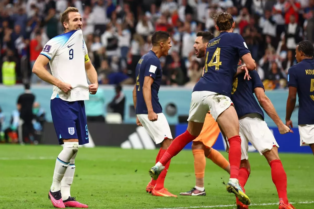 The French players celebrate while Harry Kane of England regrets his penalty kick